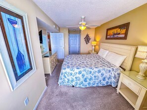 Un dormitorio con cama, ventilador de techo, mesita de noche y lámpara de pared.