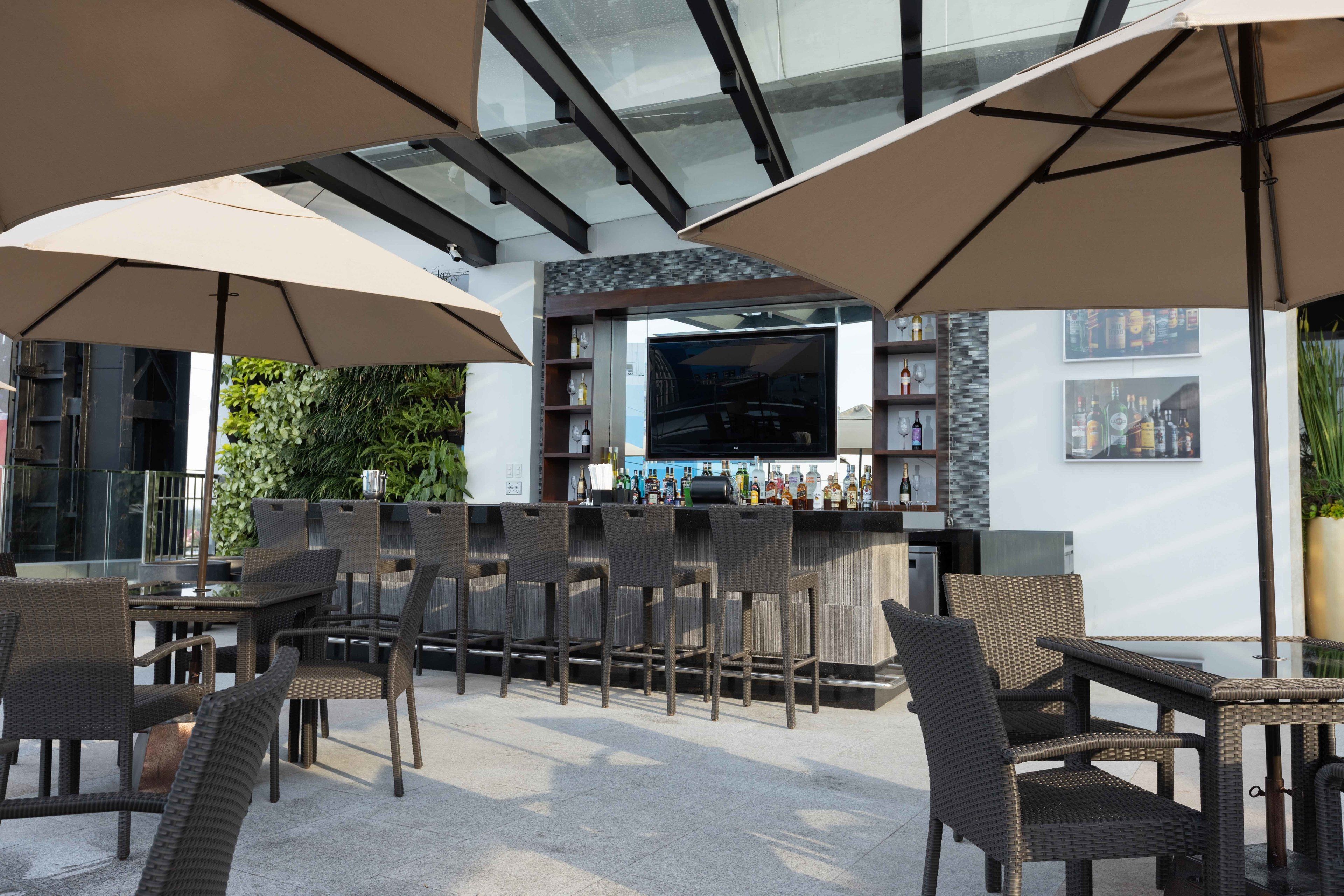Ein Außenbereich mit Bar, ausgestattet mit Korbmöbeln, einer Theke und einer Glasveranda.