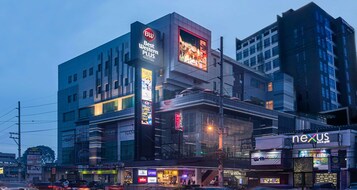 Un hotel de varios pisos con un llamativo letrero de 'Best Western PLUS', un restaurante 'Nexus' y diversos otros comercios en la planta baja.