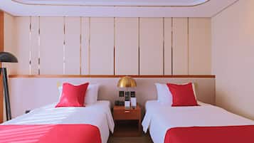 A hotel room with two beds, each with red and white bedding, a nightstand with a lamp, and a wooden headboard.