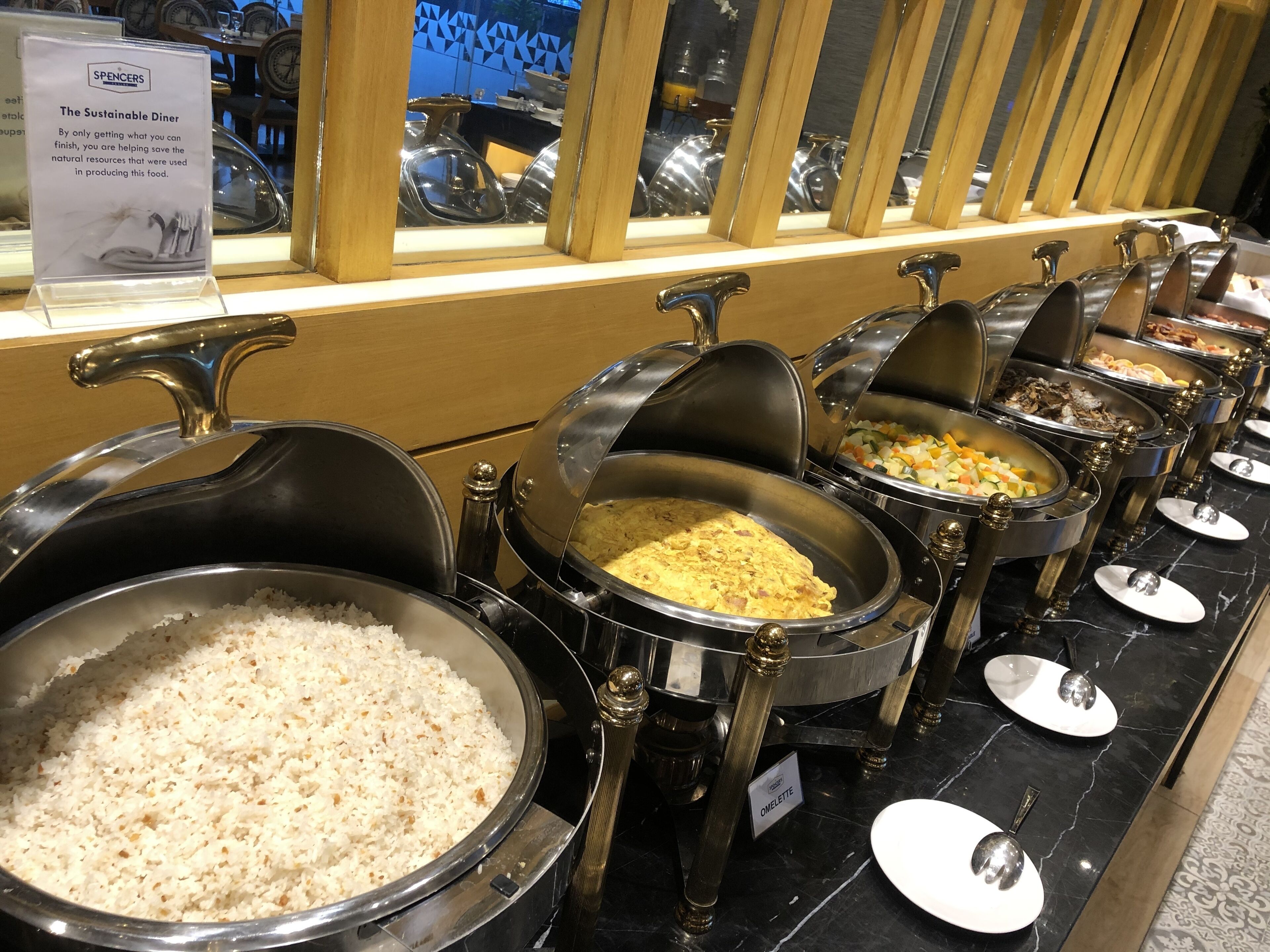 A buffet with multiple serving stations, including rice, omelette, and other dishes.