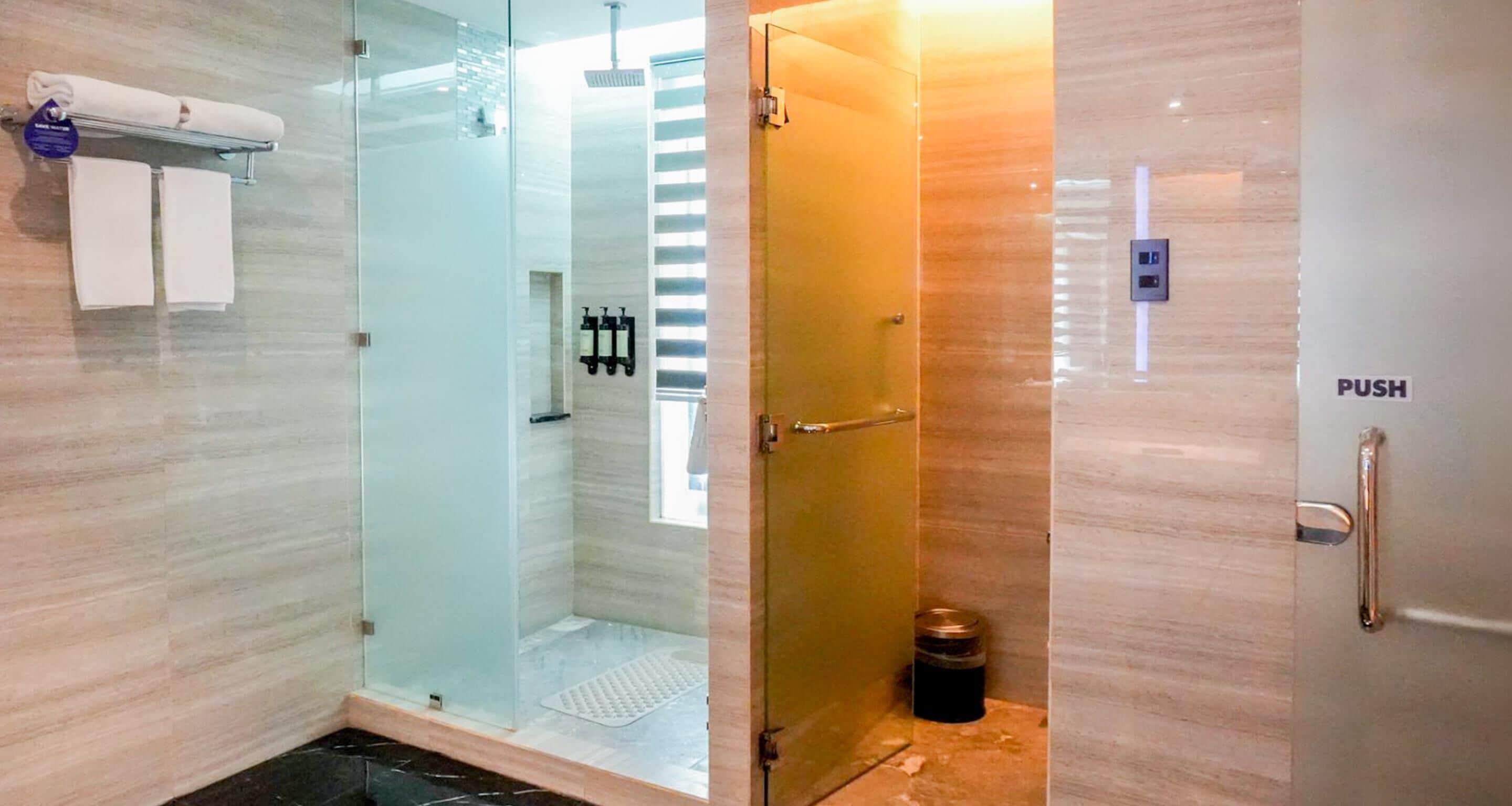 A modern bathroom with a glass-enclosed shower, a towel rack, and a push button door.