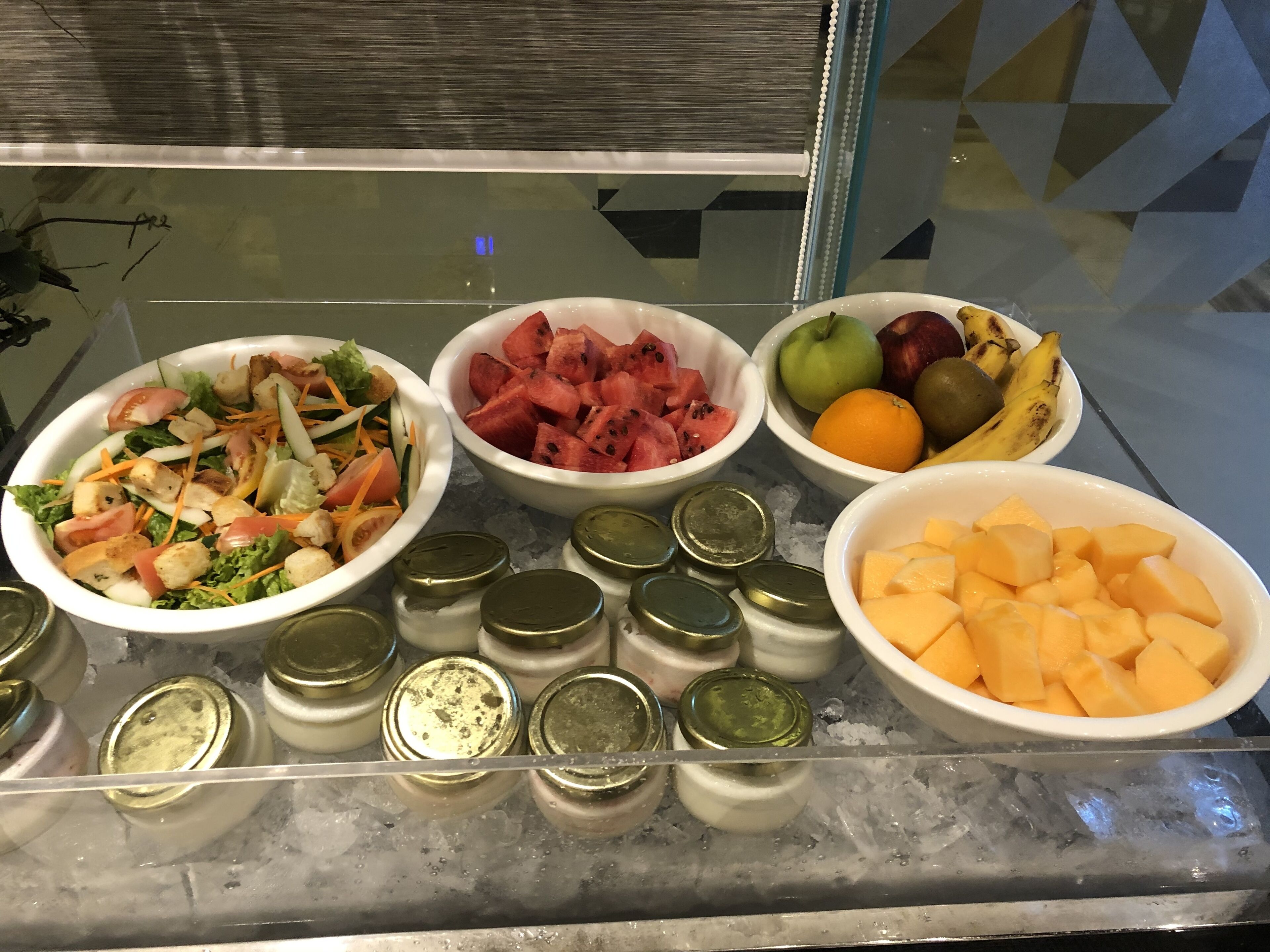 Un buffet proposant divers plats, notamment une salade, de la pastèque, des fruits et du fromage.