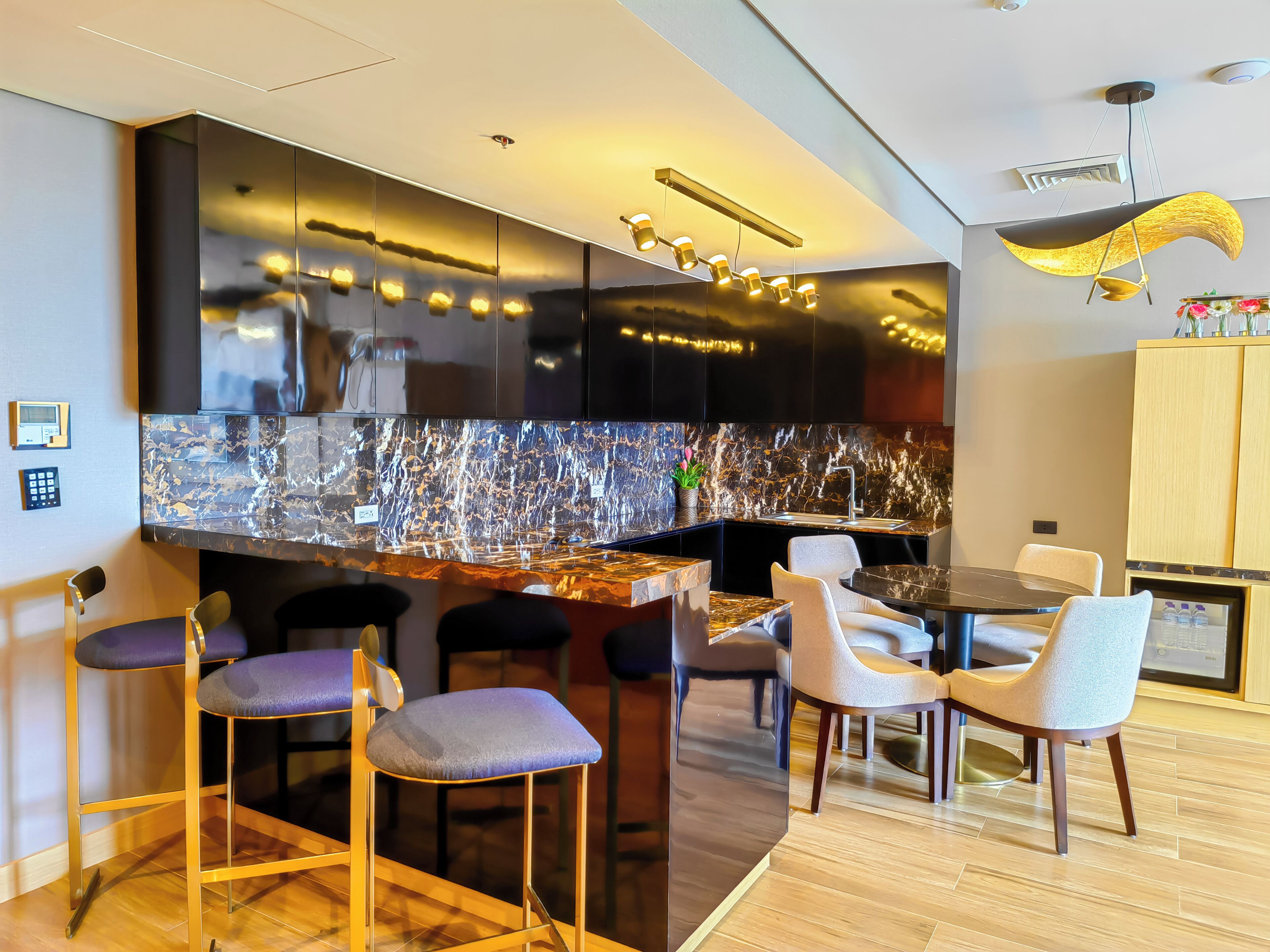 A modern kitchen with a marble countertop, bar stools, and a dining area with chairs.
