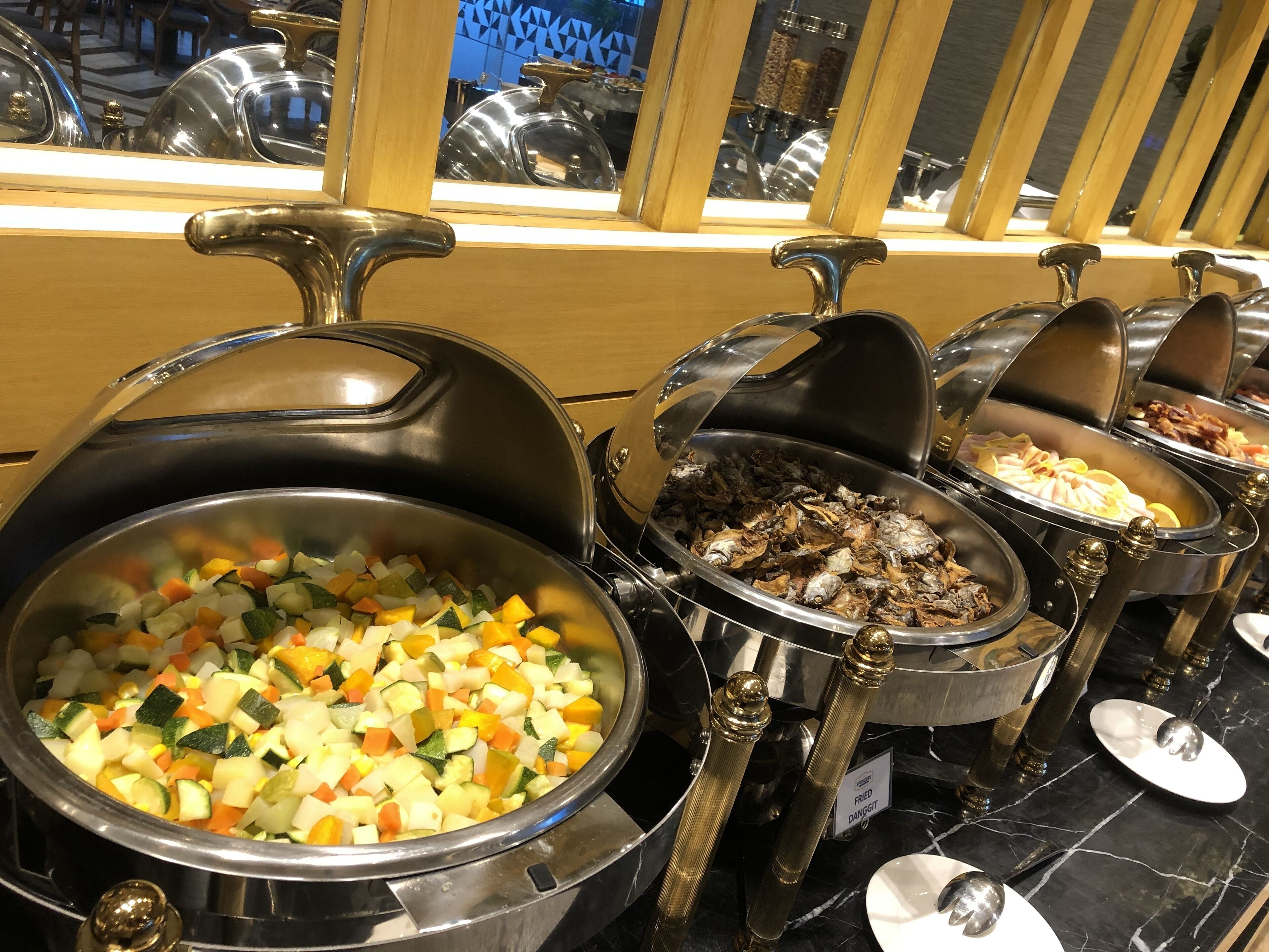 A buffet with various dishes including a vegetable mix, fried items, and other prepared foods.