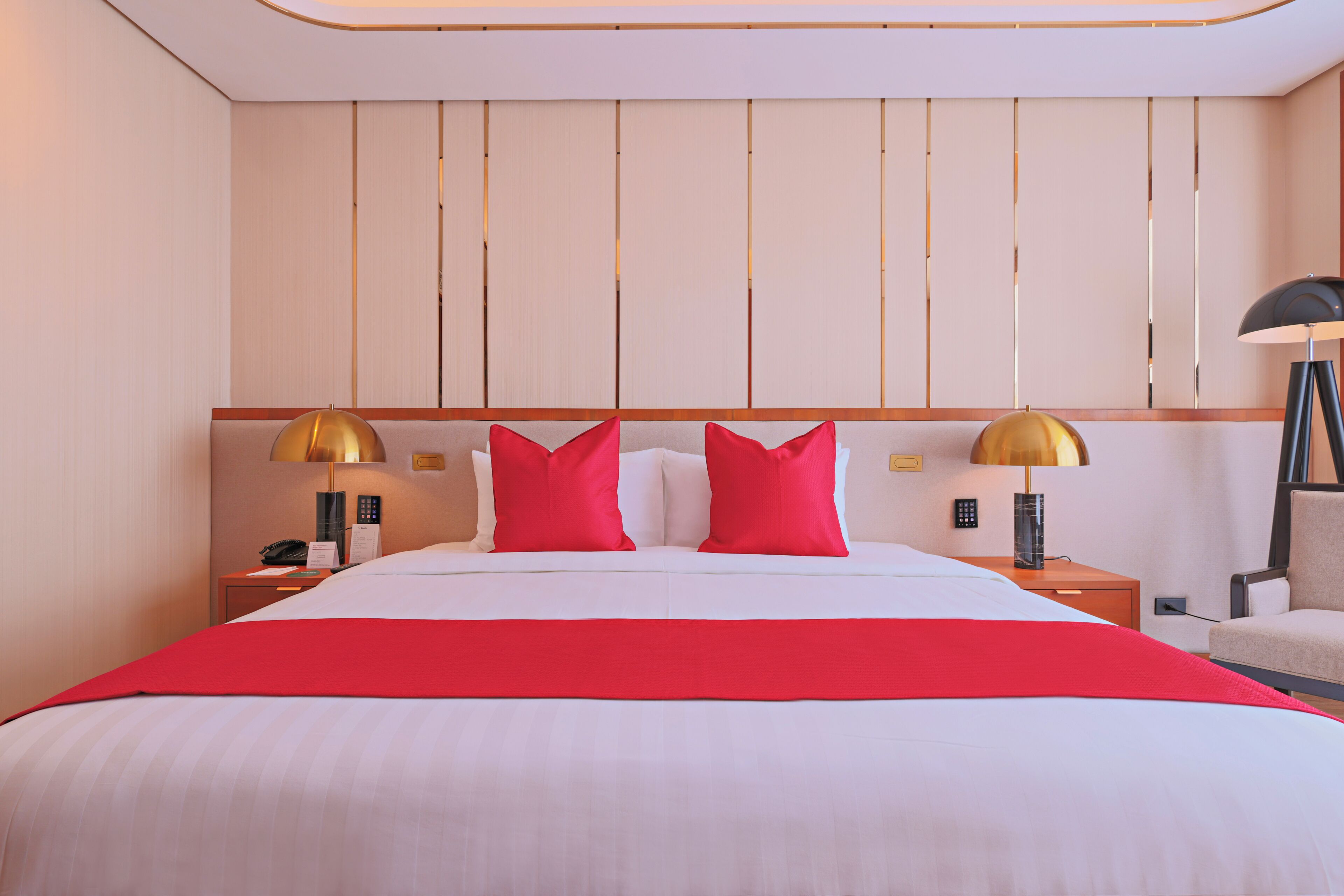 A hotel room with a large bed, two bedside tables, a lamp, and a chair.