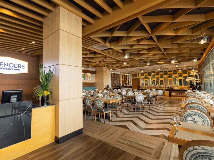 A hotel lobby with a reception desk, multiple dining tables, and chairs.