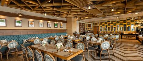 A restaurant with wooden ceiling beams, multiple dining tables with chairs, and framed artwork on the walls.