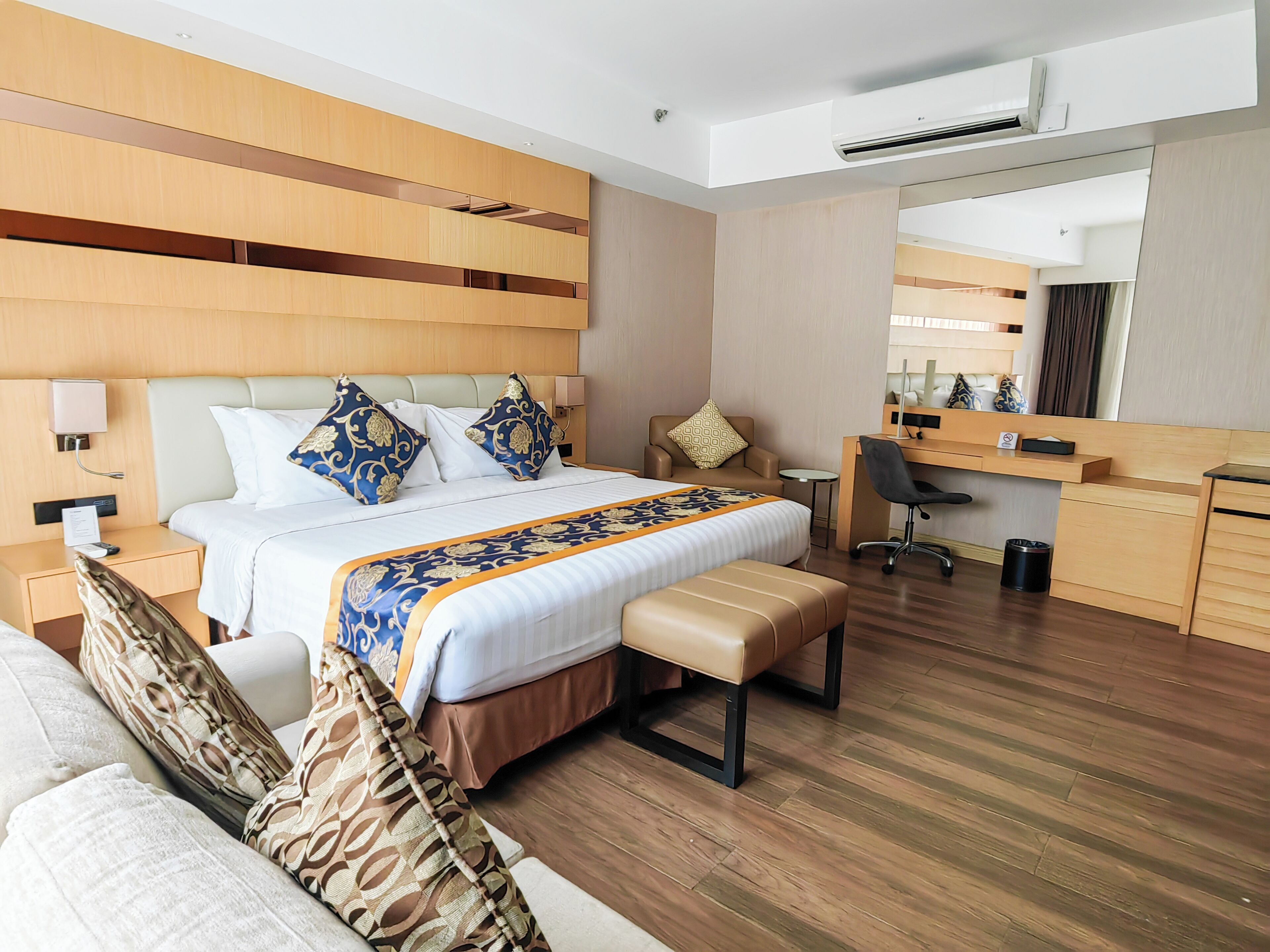 A modern hotel room with a large bed, a desk, a chair, and a small table.