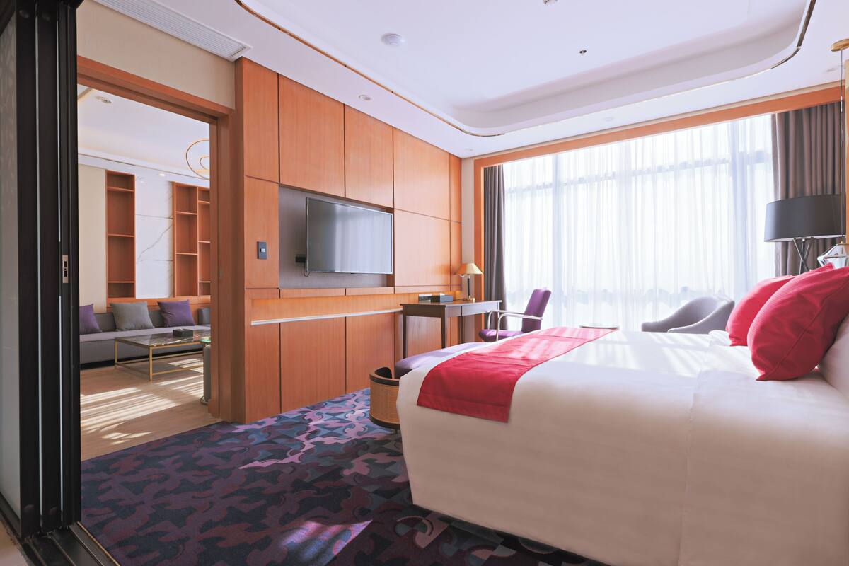 Ein modernes Hotelzimmer mit einem großen Bett, einem Schreibtisch, einem Fernseher und einem Sofa.