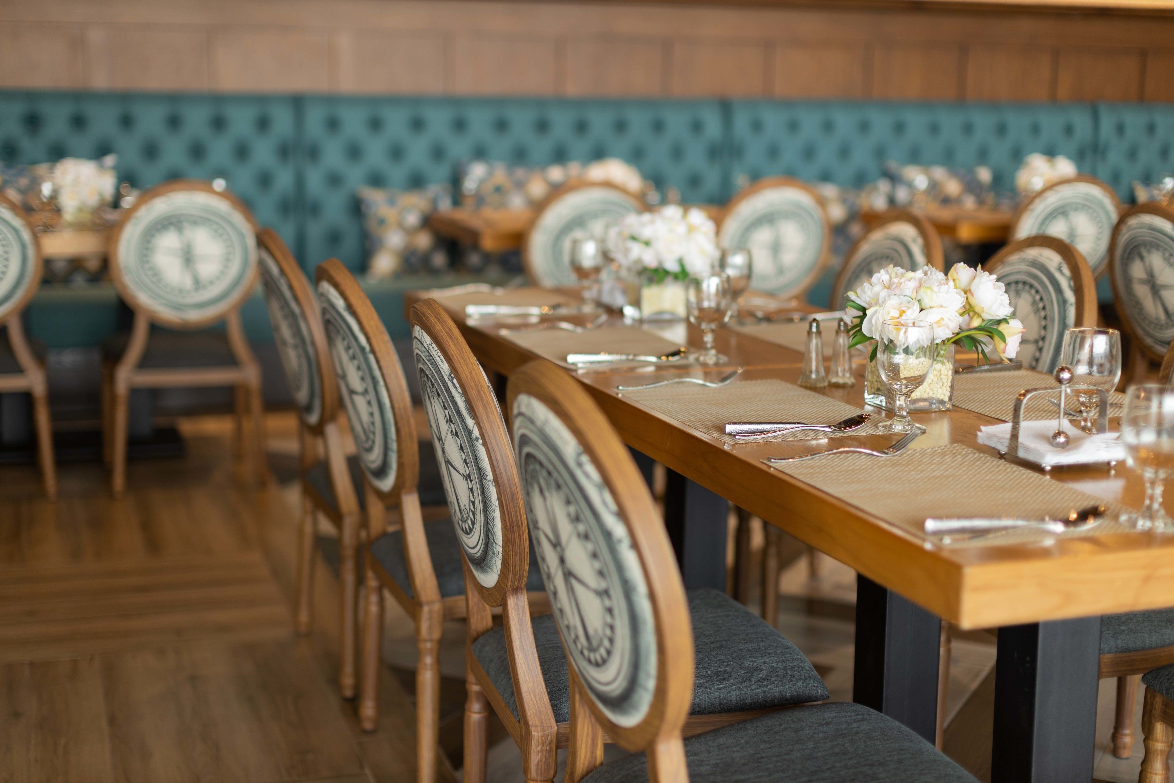 Un restaurante con mesas y sillas de madera, cada una con un cuadrante en el respaldo.