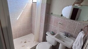 Ein Badezimmer mit Dusche, Toilette, Waschbecken und Spiegel.