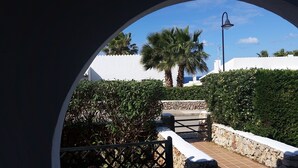 A pathway leading to a gated entrance with a stone wall and a palm tree in the background. - Comfortable Villa in Binibeca with Private Pool and Roof Terrace with Sea Views (Menorca)