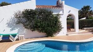 A swimming pool with a white wall and a tiled roof, surrounded by a patio area. - Comfortable Villa in Binibeca with Private Pool and Roof Terrace with Sea Views (Menorca)