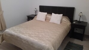 A bed with a patterned bedspread, two white pillows, and two bedside tables with lamps. - Comfortable Villa in Binibeca with Private Pool and Roof Terrace with Sea Views (Menorca)