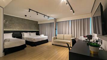 A modern hotel room with two beds, a sofa, a desk with a flat-screen TV, and a large window with curtains.