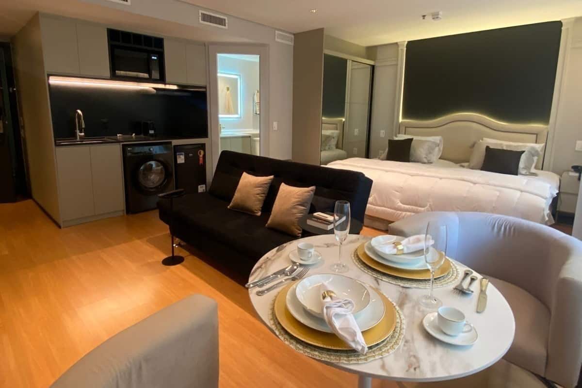 Een moderne hotelkamer met een eethoek, een bank, een bed en een kitchenette.