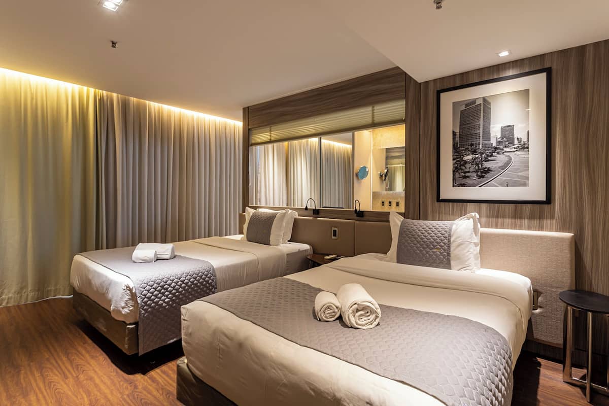 Een hotelkamer met twee bedden, een grote spiegel en een stadsgezicht aan de muur.