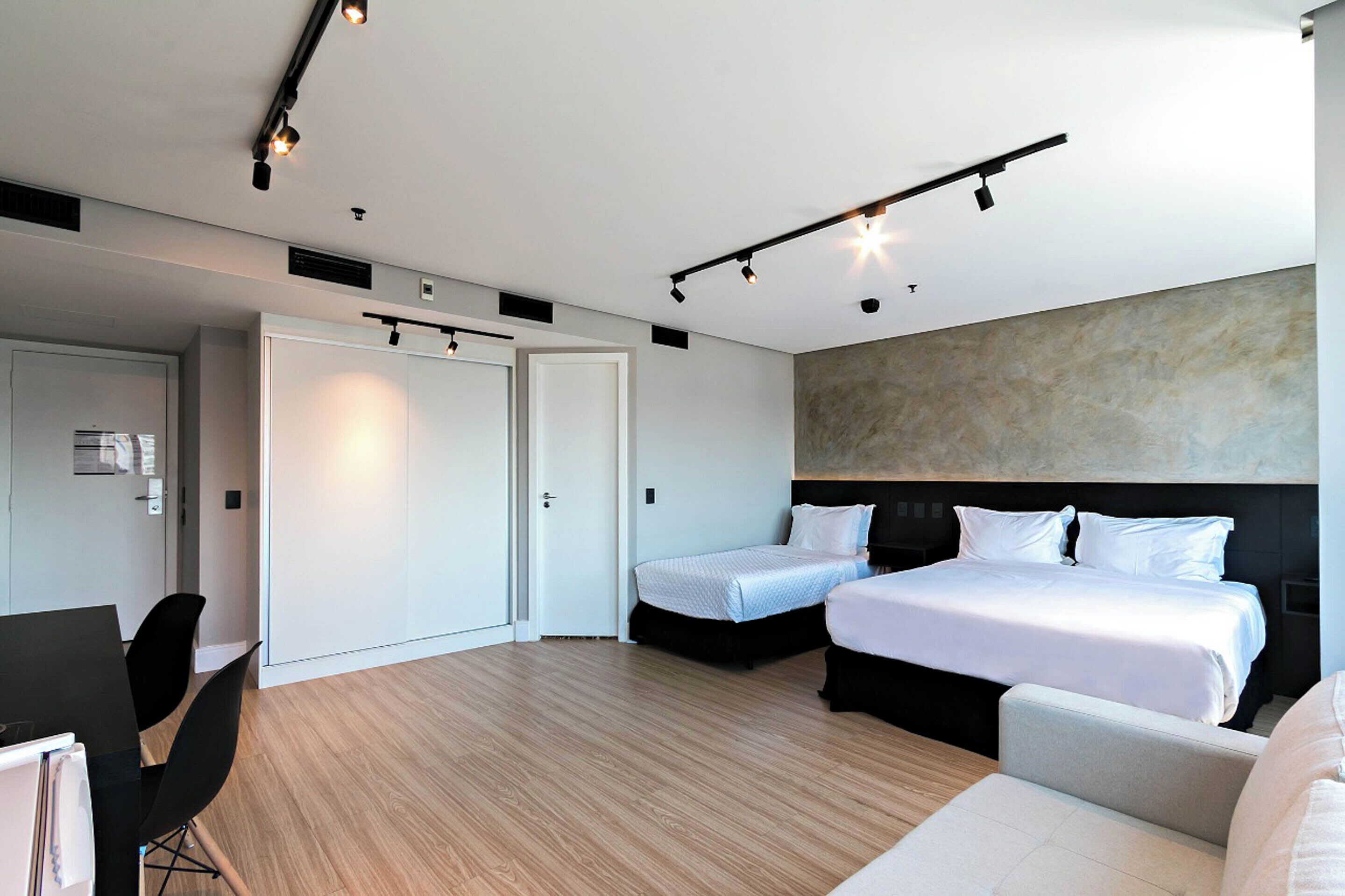 Habitación de hotel moderna con dos camas, un escritorio y una zona de estar.