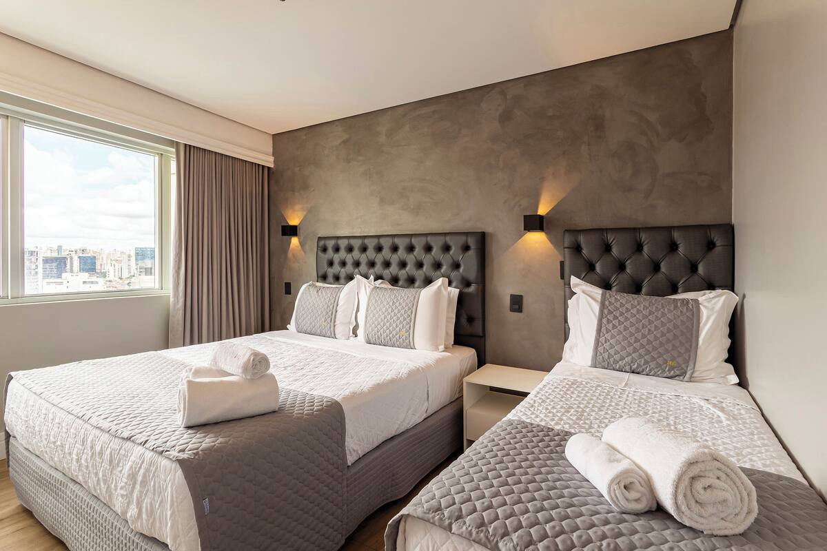 Een hotelkamer met twee bedden, een groot raam en uitzicht op de stad.