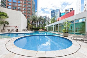 Una piscina cubierta, una piscina al aire libre, sombrillas