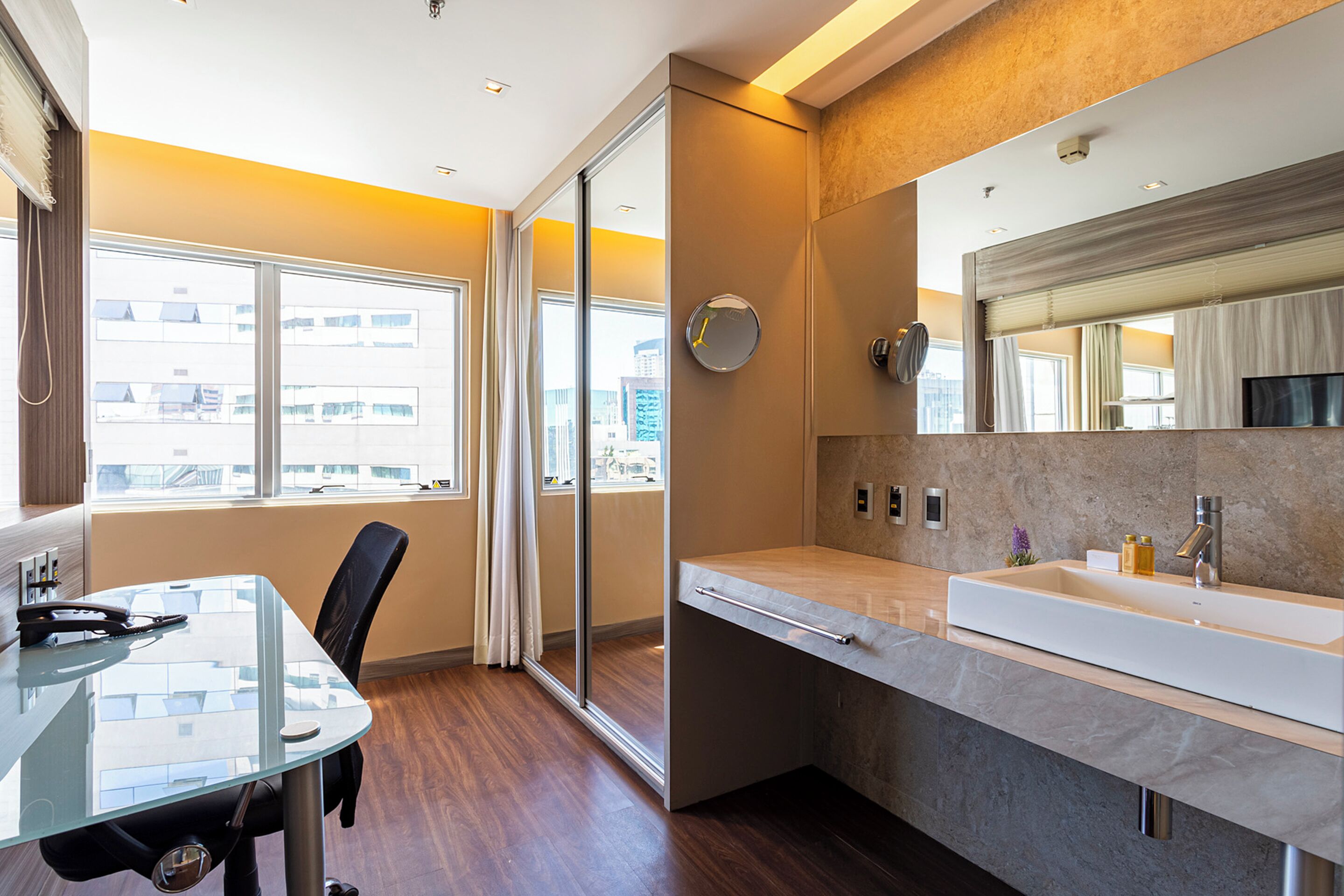 Un baño moderno con un espejo grande, un lavamanos y una cabina de ducha de vidrio.