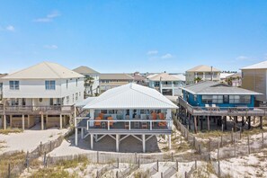 Une propriété située en bord de mer, comprenant plusieurs maisons, une terrasse couverte et une plage de sable.