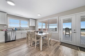 Une cuisine moderne avec des meubles blancs, un lave-vaisselle et un coin repas comprenant une table et des chaises.