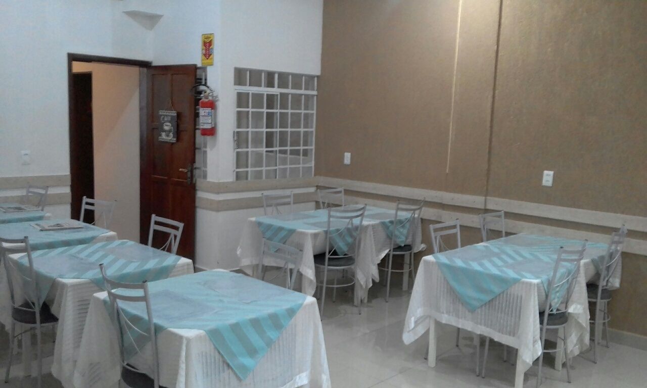 A dining area with tables and chairs, a fire extinguisher, and a window with bars.