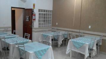 A dining area with tables and chairs, a fire extinguisher, and a window with bars.