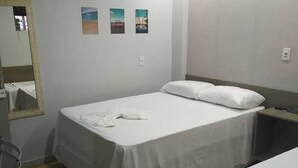 Ein Hotelzimmer mit zwei Betten, einem Spiegel und drei kleinen Wandbildern.