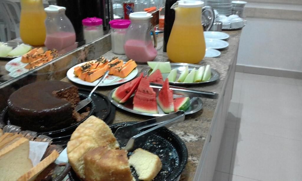 A buffet with various food items including a chocolate cake, watermelon slices, and different types of bread.