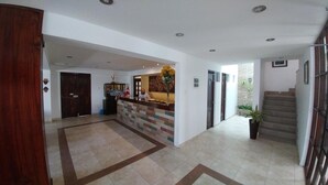 A reception area with a counter, a staircase, and a potted plant. - Casa de Lucila (Chivay)