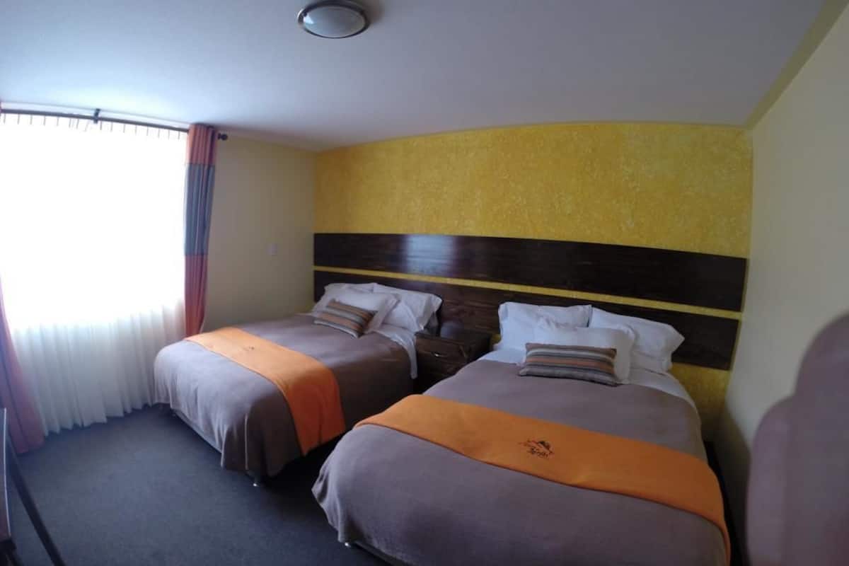 A hotel room with two beds, each with a brown and orange bedspread, and a yellow textured wall.