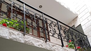 A building with a balcony featuring wrought iron railings and potted plants. - Casa de Lucila (Chivay)