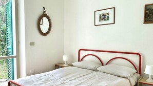 A bedroom with a bed, a bedside table, a mirror, and a framed picture on the wall. - N107 - Numana, large three-room apartment with garden and two bathrooms (Numana)