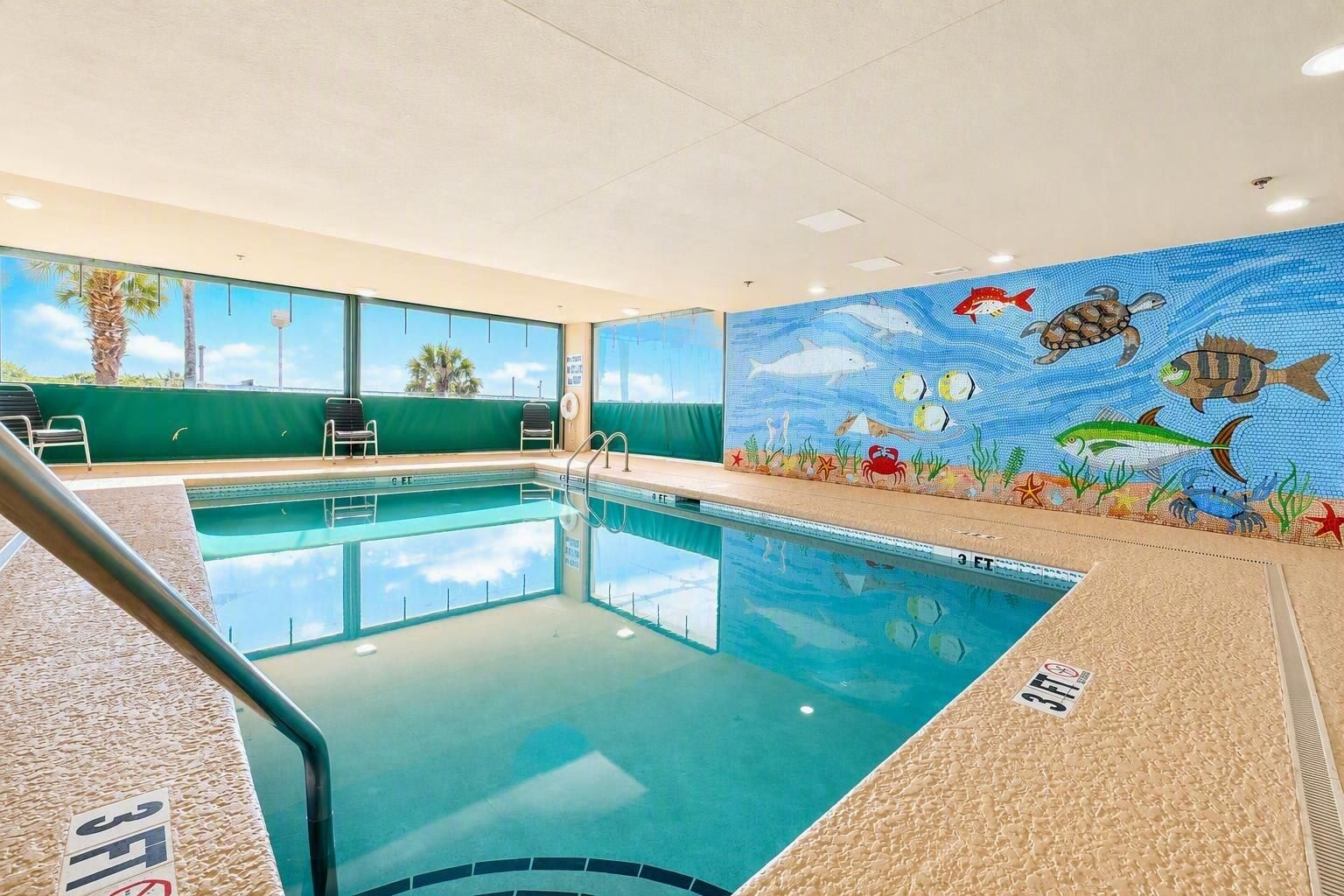 An indoor swimming pool with a mural of marine life on the walls.