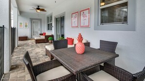 A covered patio with wicker furniture, a ceiling fan, and framed artwork on the wall. - Champions Gate Exec Villas- 9026sd (Davenport)