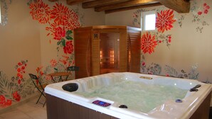 Un bain à remous dans une pièce dont les murs sont recouverts d’un papier peint à motifs floraux et dont le plafond est en bois.