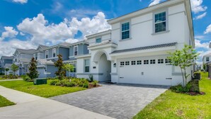 A modern two-story house with a garage, a driveway, and a well-maintained lawn. - Champions Gate Exec Villas- 1586sandb (Davenport)