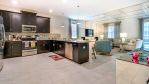 Una cocina moderna con armarios oscuros, electrodomésticos de acero inoxidable y una isla central.