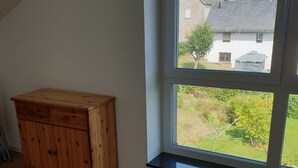 Une pièce dotée d’une grande fenêtre, d’un plancher en bois et d’une armoire en bois.