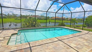 A swimming pool with a view of a lake and houses in the background.