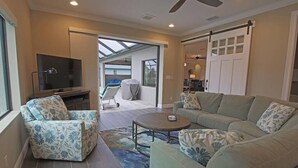 A spacious living area with a sofa, armchair, and a television.