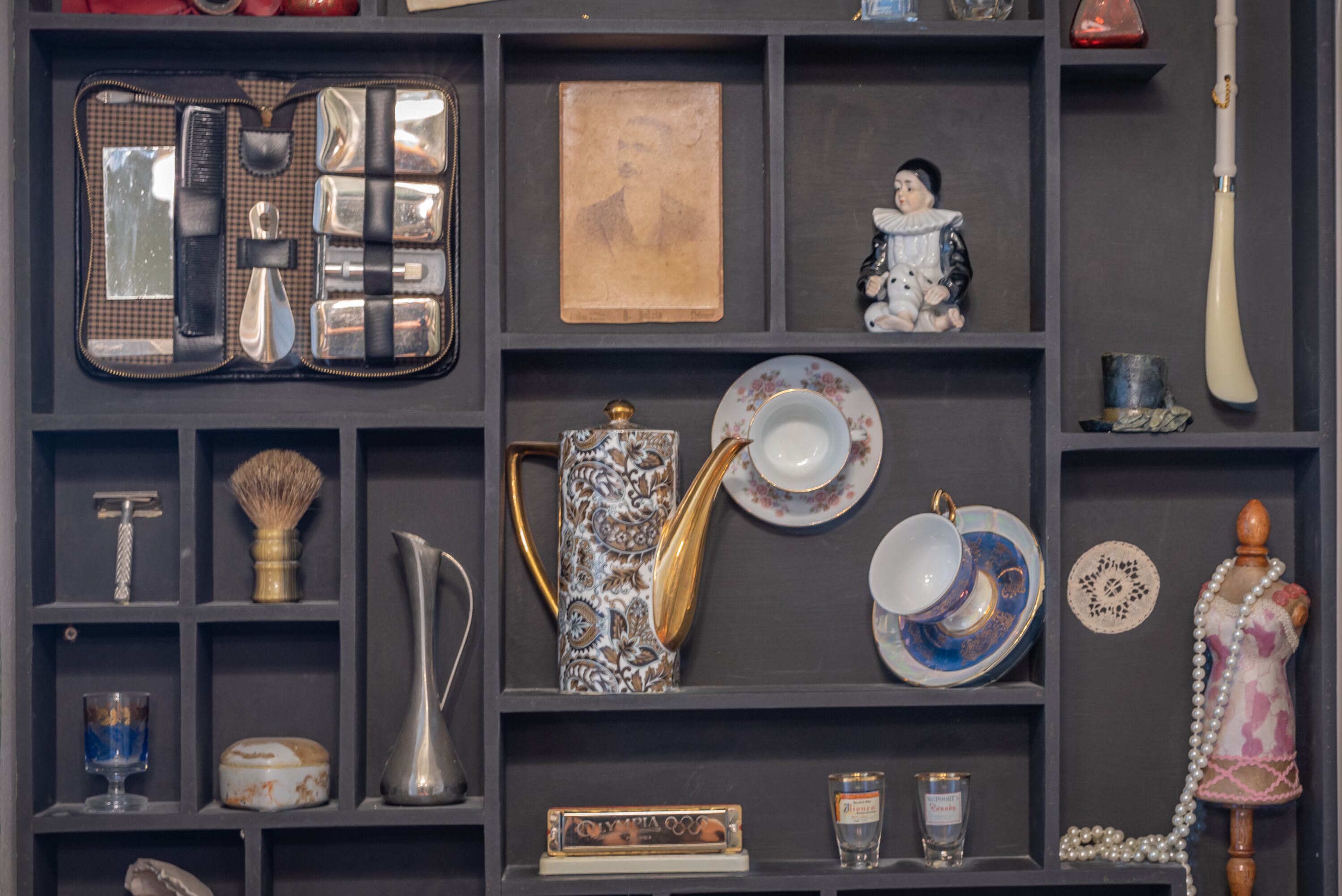 A display of vintage and antique items including a vintage radio, a decorative teapot, and a collection of porcelain plates and cups.
