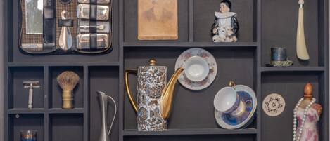 A display of vintage and antique items including a vintage radio, a decorative teapot, and a collection of porcelain plates and cups.
