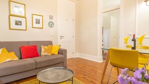 A living room with a sofa, a coffee table, and a dining area with chairs and a table. - Portuguese Charm in Lisbon (Lisboa)