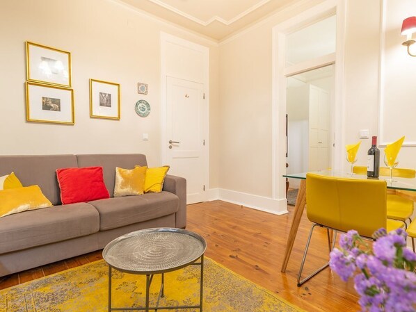 A living room with a sofa, a coffee table, and a dining area with chairs and a table.