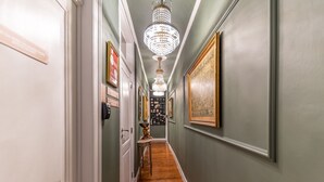 A hallway with a chandelier, framed artwork, and a wooden floor. - Portuguese Charm in Lisbon (Lisboa)