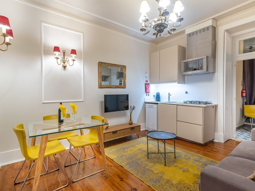 A modern living space with a dining area, kitchen, and a sofa.